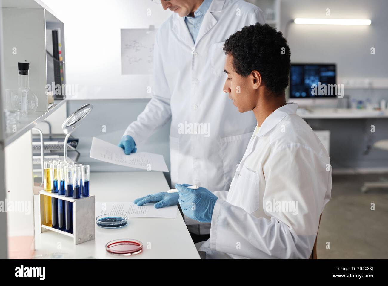 Ritratto con vista laterale di due scienziati che lavorano con documenti in laboratorio, spazio copia Foto Stock