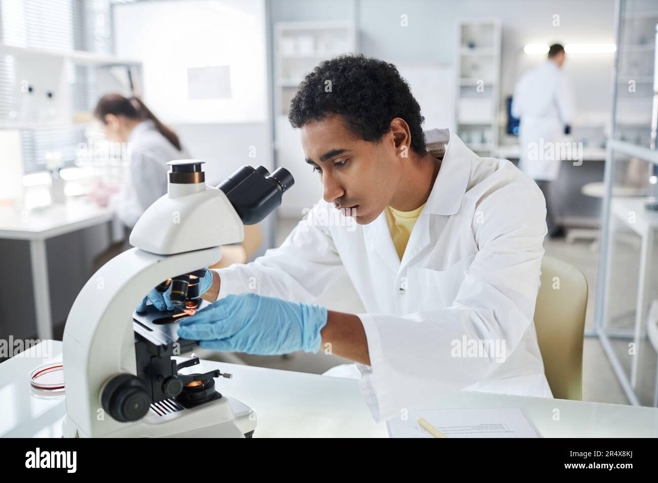 Ritratto di giovane scienziato etnico che allestiscono un microscopio elettronico in laboratorio, copia spazio Foto Stock