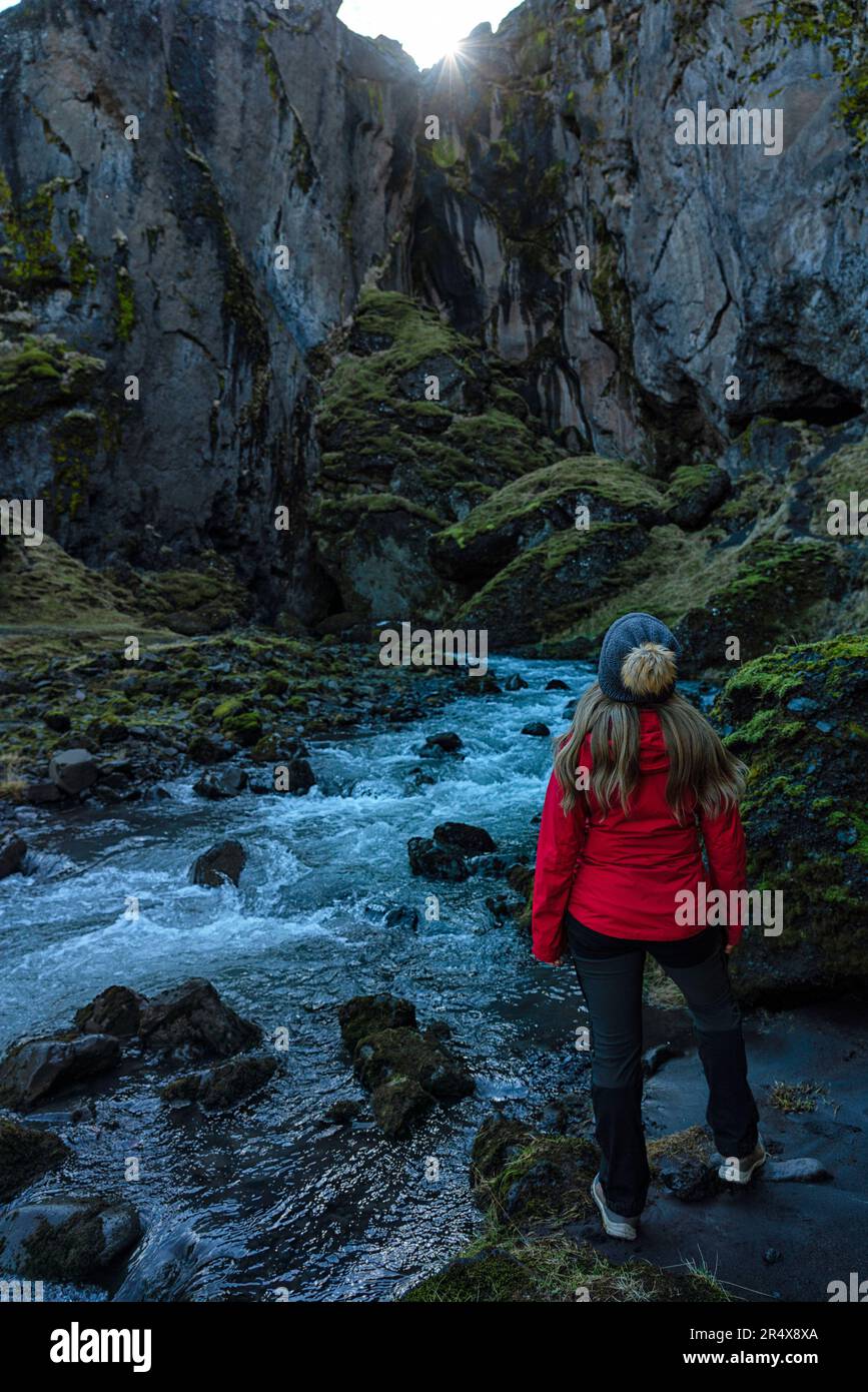 Vista da dietro di una donna che esplora i canyon e il paesaggio di Thorsmork, un'area di eccezionale bellezza nel sud dell'Islanda Foto Stock