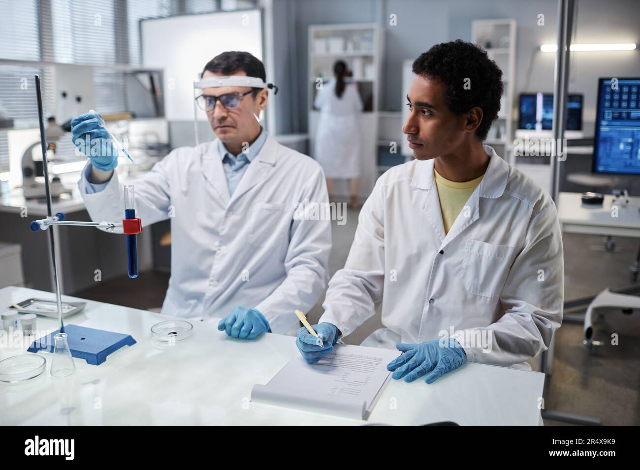 Ritratto di giovane interno in laboratorio scientifico guardando scienziato maschile al lavoro Foto Stock