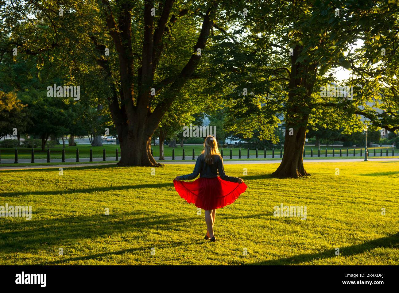 La ragazza adolescente si staglia con la luce del sole che splende attraverso una gonna rossa sul terreno del Campidoglio degli Stati Uniti Foto Stock