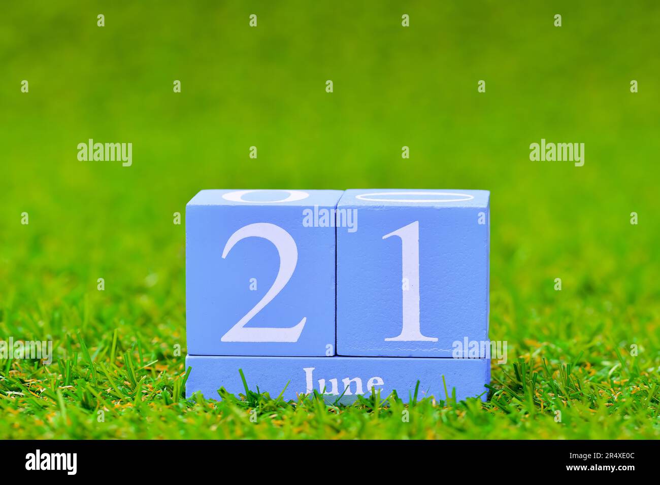 Data giugno 21 su calendario blocco blu, primo giorno d'estate, verde erba campo di calcio sfondo. Profondità di campo ridotta sfondo bokeh sfocato con Foto Stock