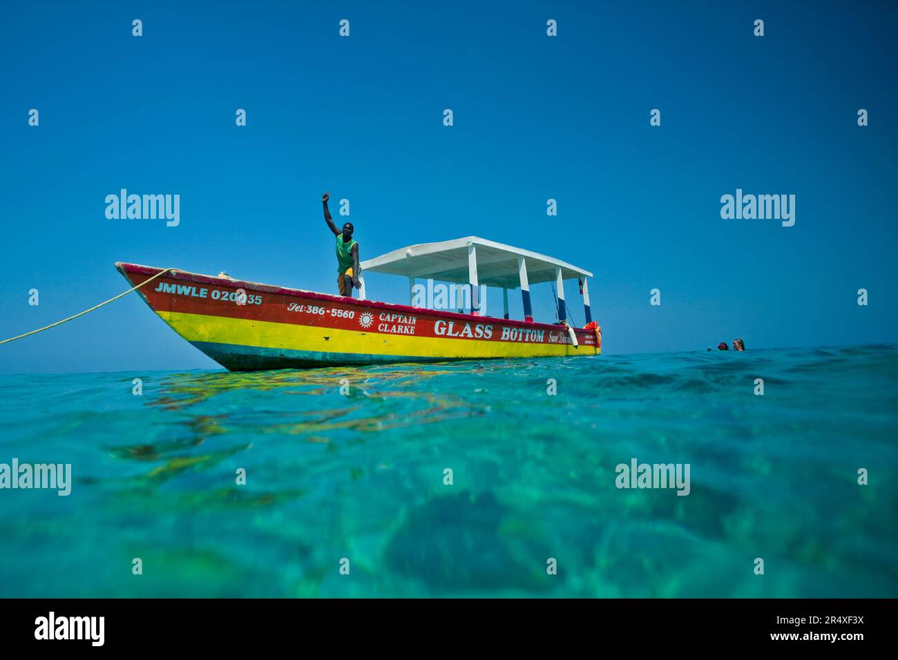 La guida del tour salta dalla sua barca con fondo in vetro nei Caraibi; Negril Beach, Giamaica, Indie occidentali Foto Stock
