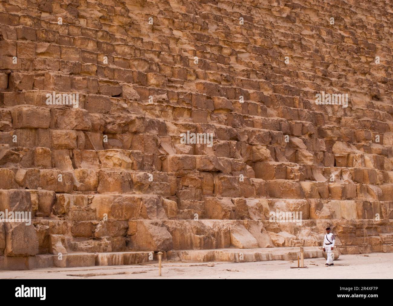 L'uomo cammina alla base della grande Piramide di Giza; Giza, Egitto Foto Stock