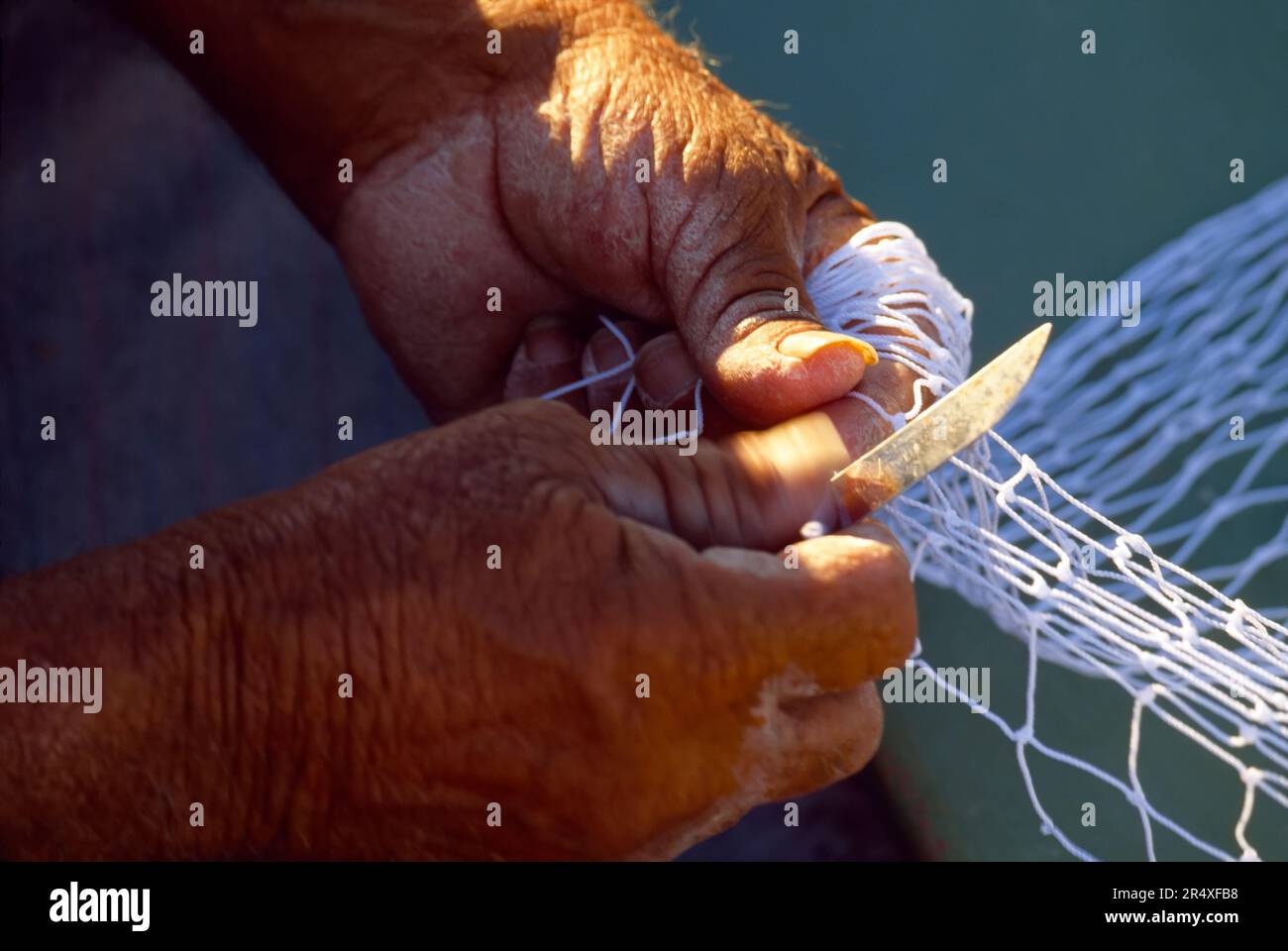 Fisherman mending a NET, view of Hands; Marsaxlokk, Malta Island, Repubblica di Malta Foto Stock