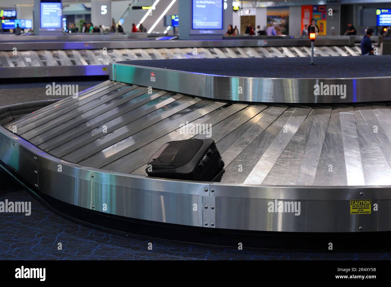 Una valigia su un carosello per i bagagli presso un'area di ritiro bagagli degli arrivi dell'aeroporto. Foto Stock