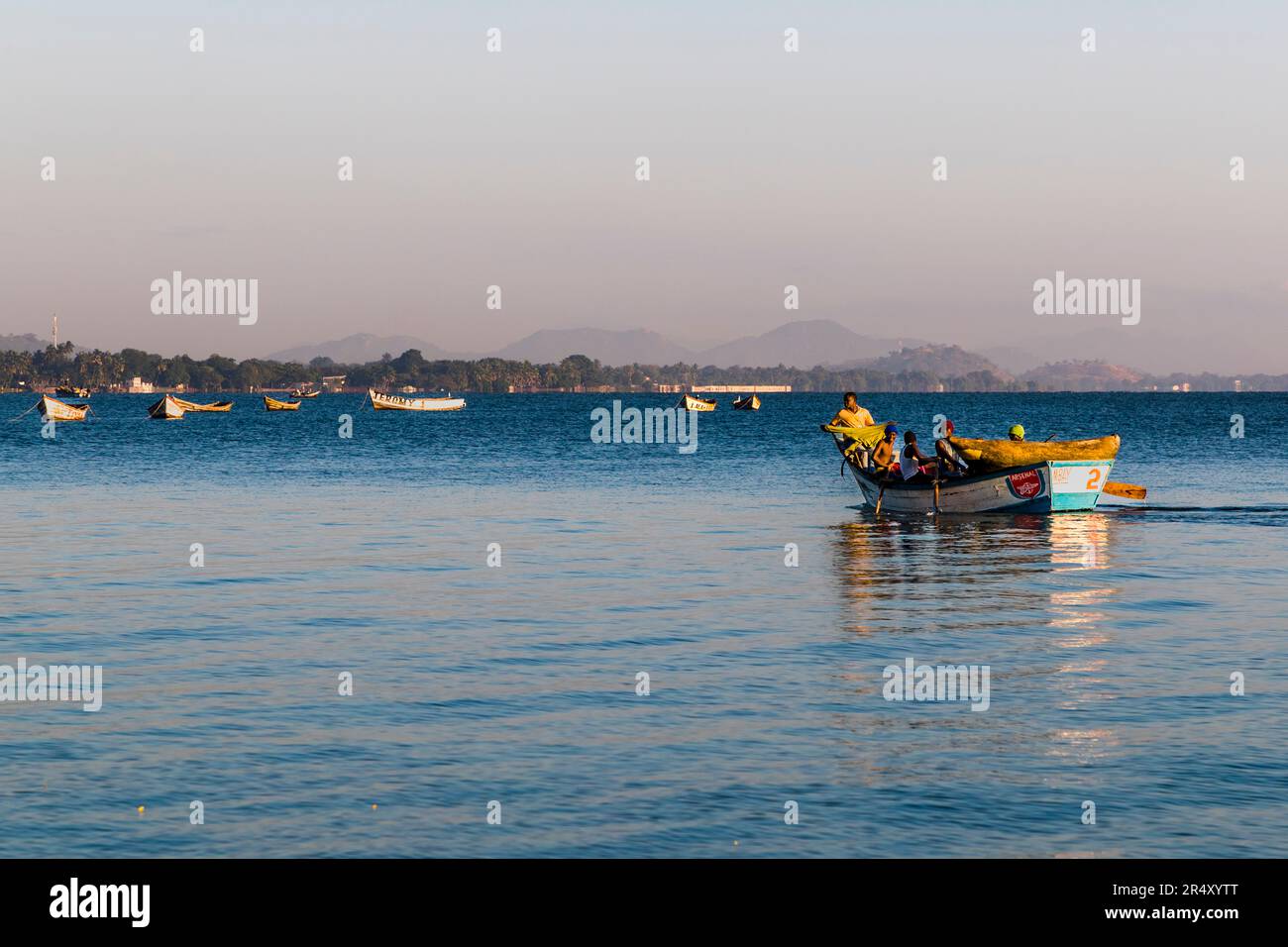 Lago Malawi, uomini in viaggio verso un piccolo porto di pescatori vicino a Makawa. La barca a remi porta anche una canoa da sgambino per la pesca tradizionale Foto Stock