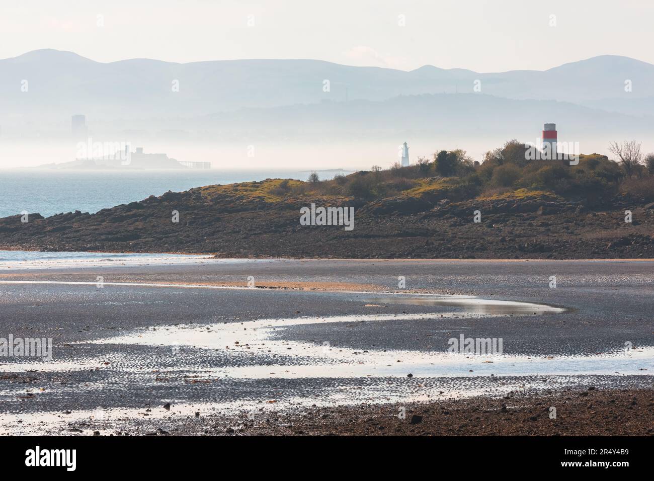 Moody, vista misteriosa a bassa marea da Silversands Beach ad Aberdour, Fife, Regno Unito attraverso il Firth of Forth a Edimburgo, e le Pentland Hills in Scozia. Foto Stock