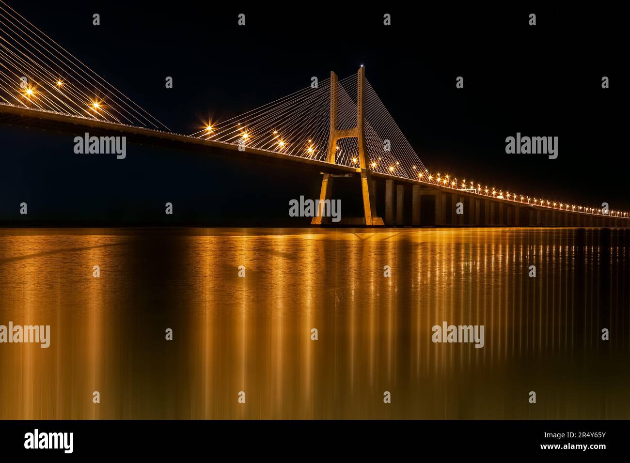 Riflessioni dorate sul ponte Vasco da Gama di notte Foto Stock