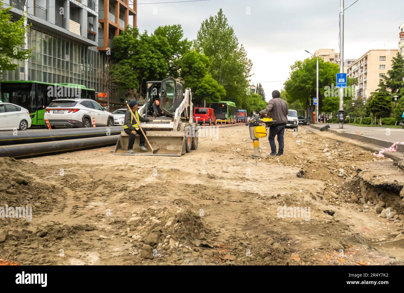 Tbilisi Georgia lavori stradali. Operai, macchina bulldozer che ripara lavori di costruzione di strade. Foto Stock