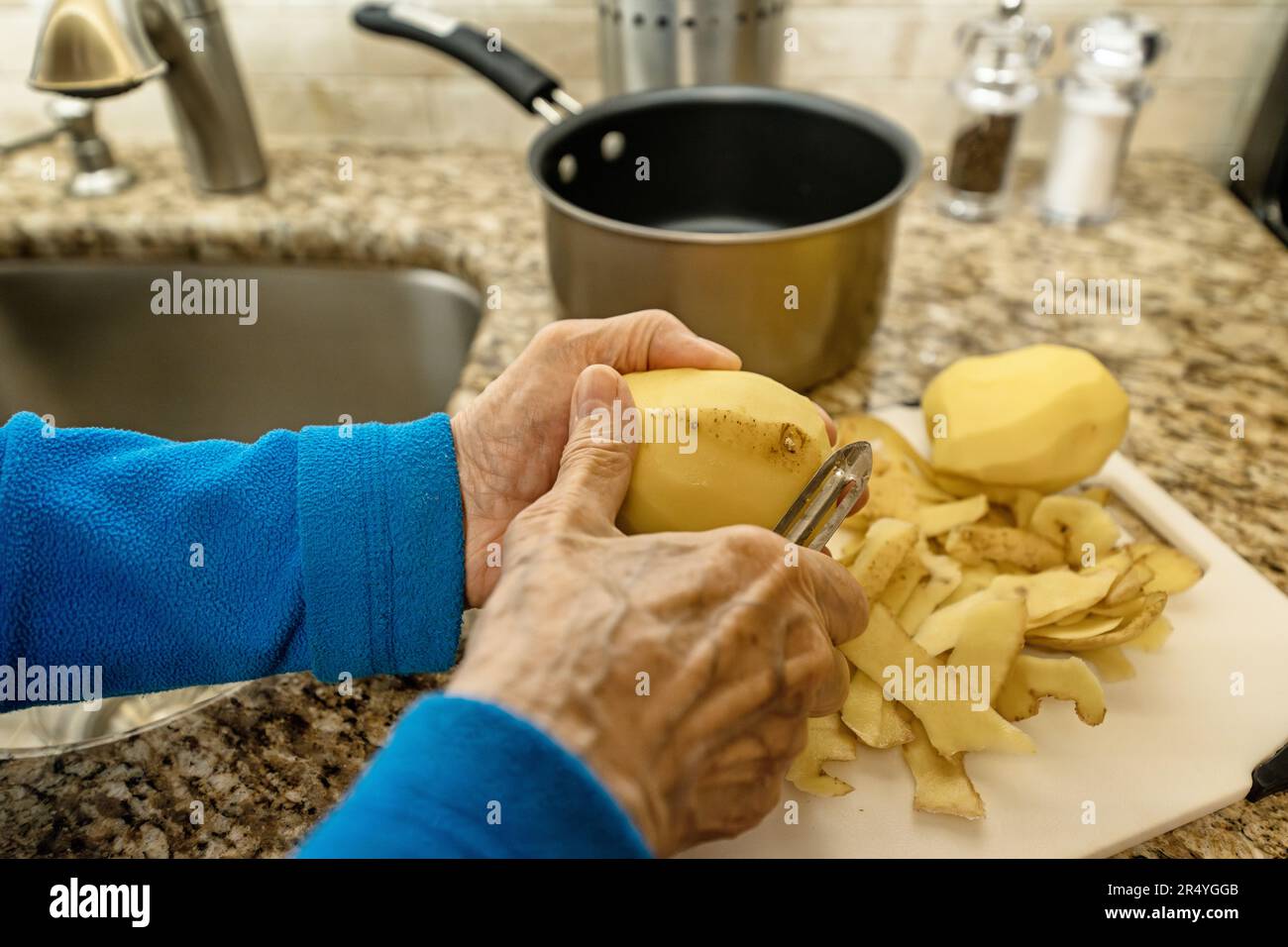 Donna anziana mani Peeling patate Foto Stock