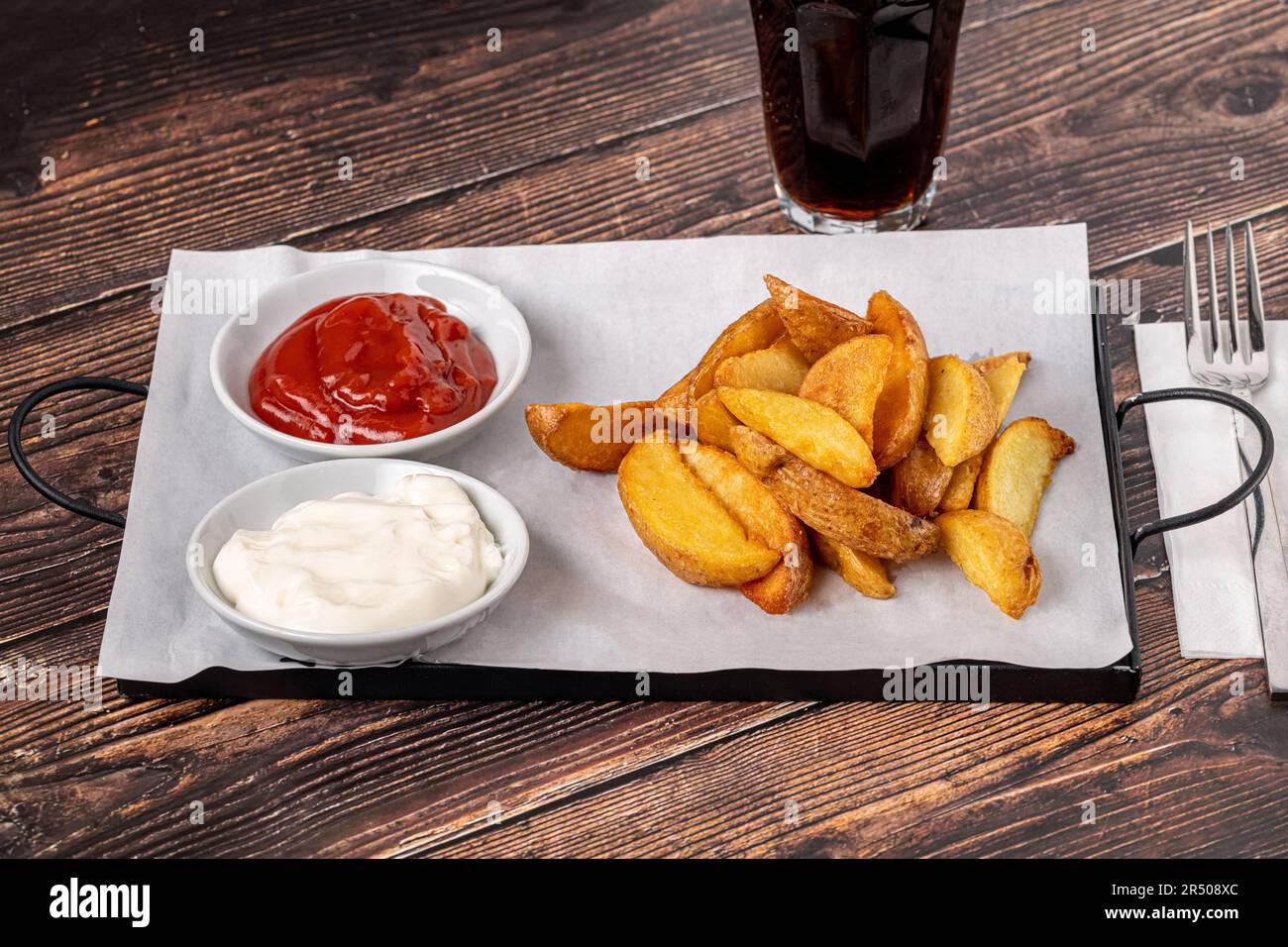 Spicchi di patate con ketchup e maionese su tavolo di legno Foto Stock