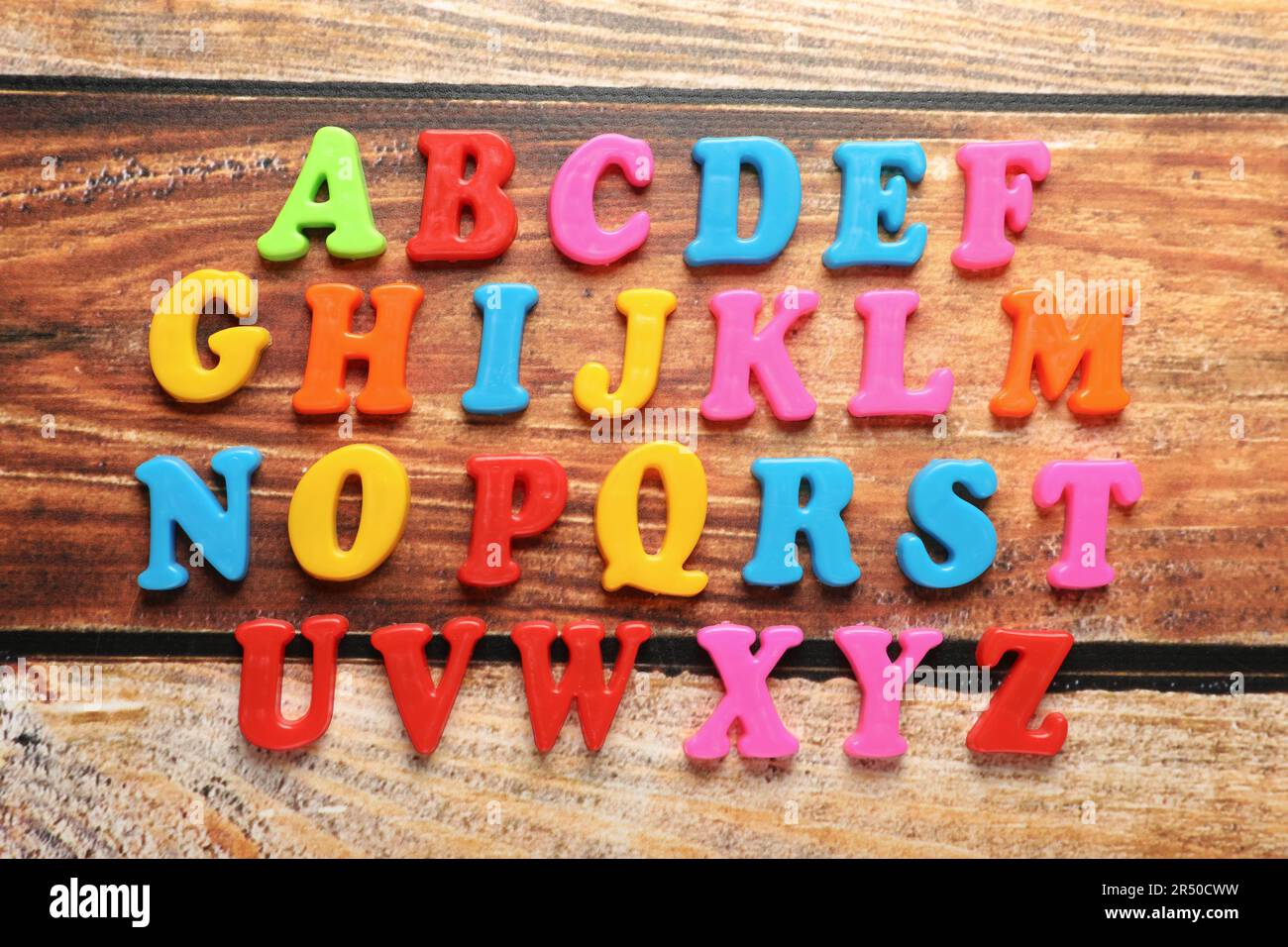 Lettere magnetiche colorate su tavolo di legno, piatto. Ordine alfabetico Foto Stock