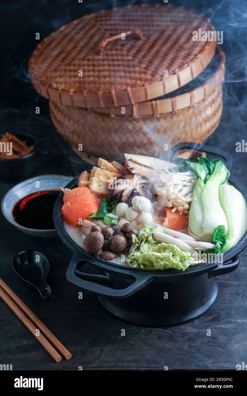 Pentola calda con cavolo cinese e funghi, cucinata in un brodo cremoso e abbondante di latte di soia Foto Stock