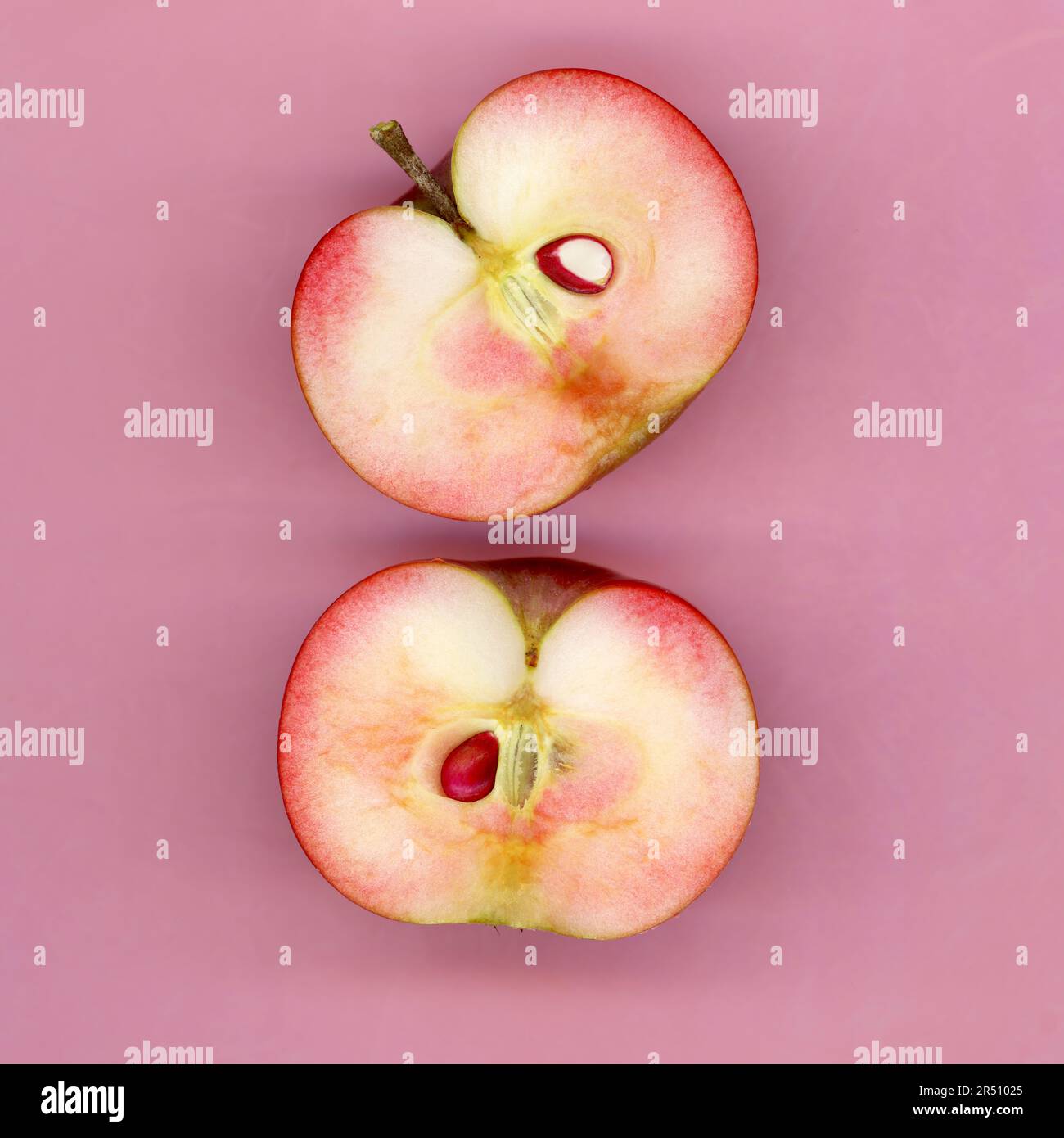 Due mezze mele su sfondo rosa Foto Stock