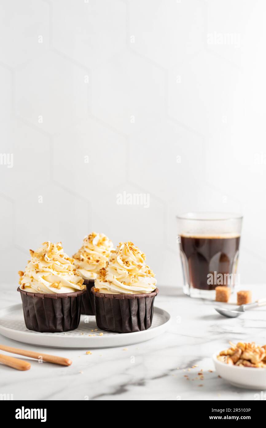 Cupcake con glassa alla vaniglia e noci tritate Foto Stock