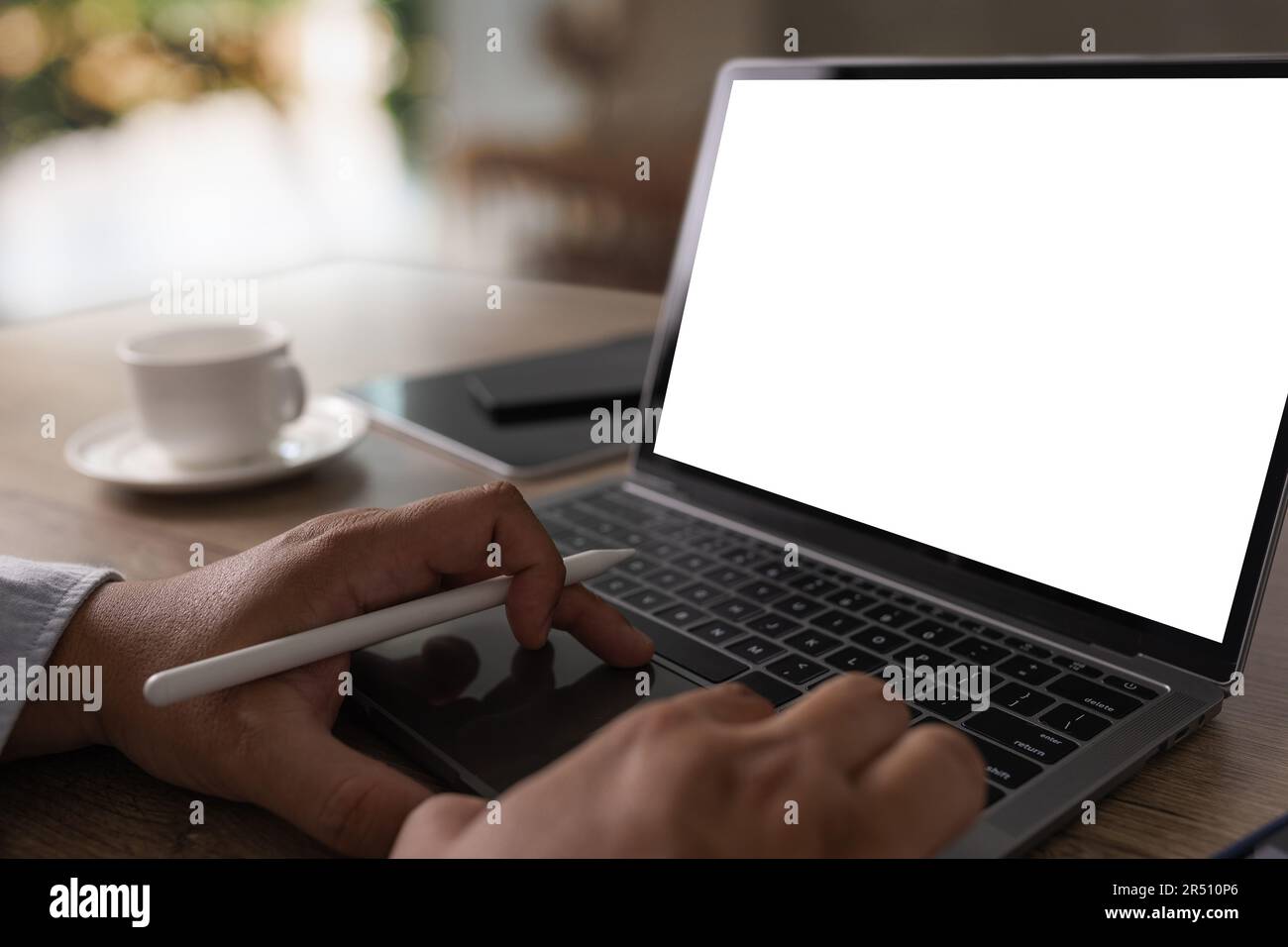 Computer portatile con schermo vuoto sul tavolo interno, l'uomo al suo luogo di lavoro utilizzando la tecnologia Foto Stock