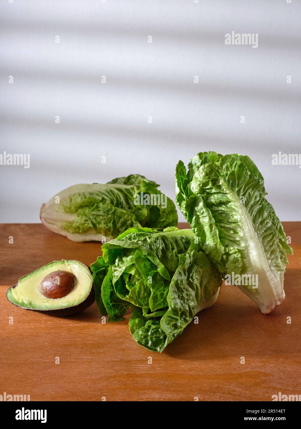 Lattuga romana e mezzo avocado su un banco di legno Foto Stock
