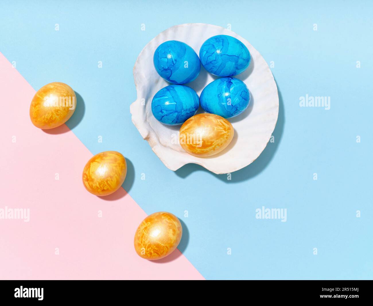 Uova di Pasqua gialle e blu con guscio su sfondo blu e rosa Foto Stock