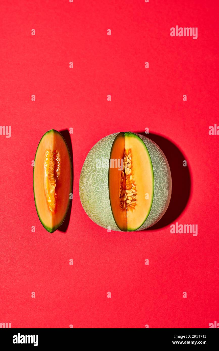 Melone cantaloupe, tagliato, su sfondo rosso Foto Stock