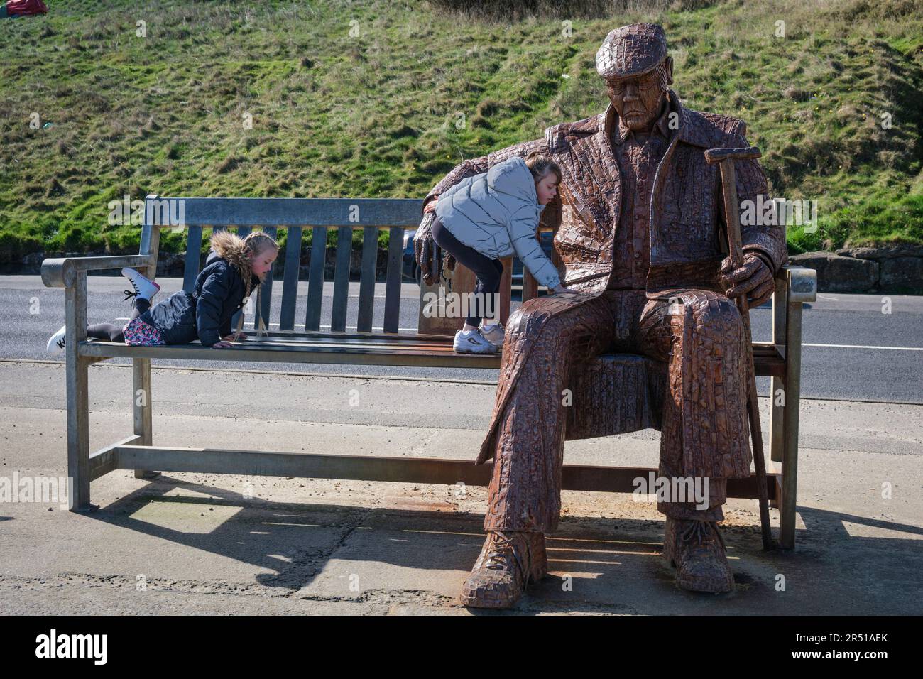 Bambini che si arrampicano sulla scultura 'Freddie Gilroy and the Belsen Straggler' di Ray Lonsdale, North Bay, Scarborough, Yorkshire Foto Stock