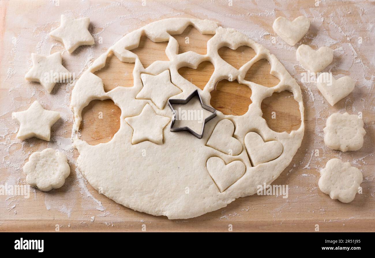 Il processo di taglio dei biscotti di formaggio di ricotta con gli stampi da pasta molle rotolati fuori su una tavola. Cucinare deliziose torte fatte in casa Foto Stock