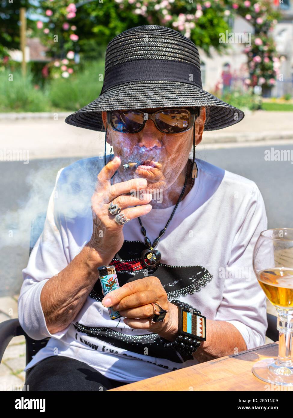 Donna anziana che fuma un piccolo sigaro al tavolo del caffè - Francia. Foto Stock