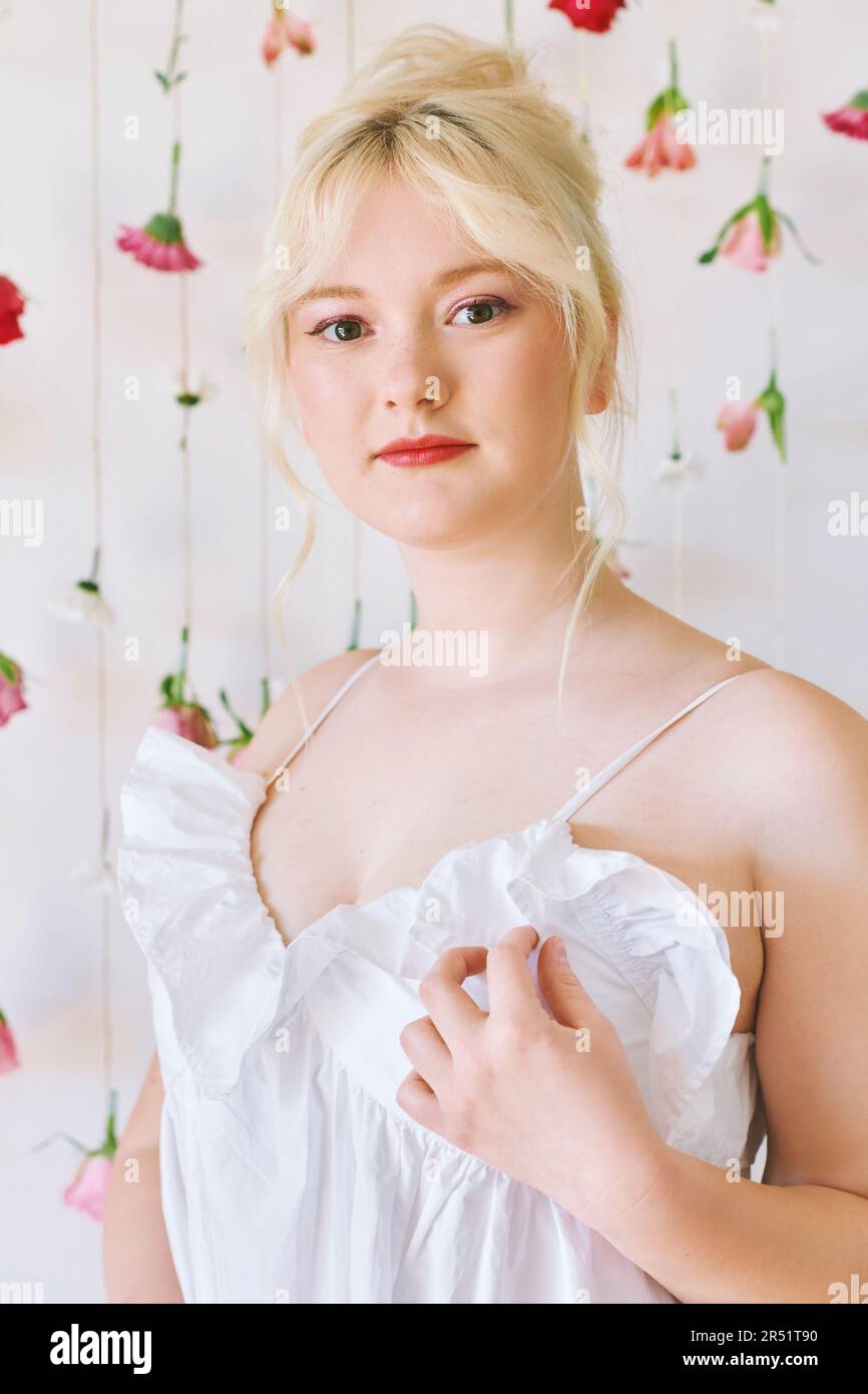 Studio ritratto di bella giovane adolescente 15 - 16 anni ragazza vestito estivo, posa su sfondo bianco con fiori appesi, bellezza e moda Foto Stock