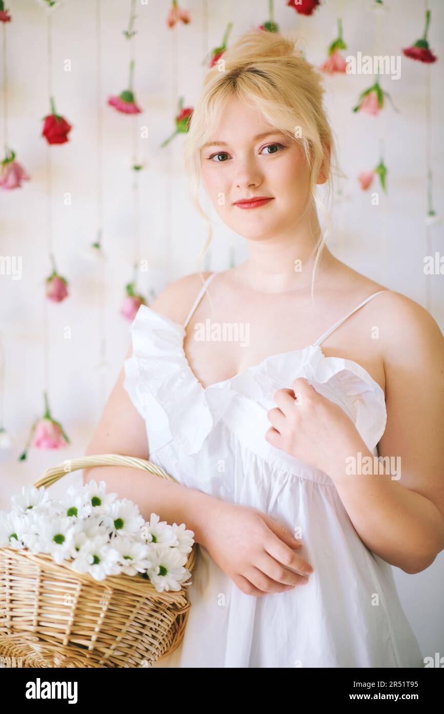 Studio ritratto di bella giovane adolescente 15 - ragazza di 16 anni che indossa abito estivo, posa su sfondo bianco con rose pendenti, cestello con Foto Stock