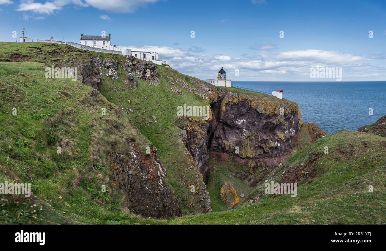 Faro di St Abbs Head, foghorn e casa del guardiano del faro sulla cima delle scogliere rocciose con mare blu calmo piatto e orizzonte sullo sfondo. Foto Stock