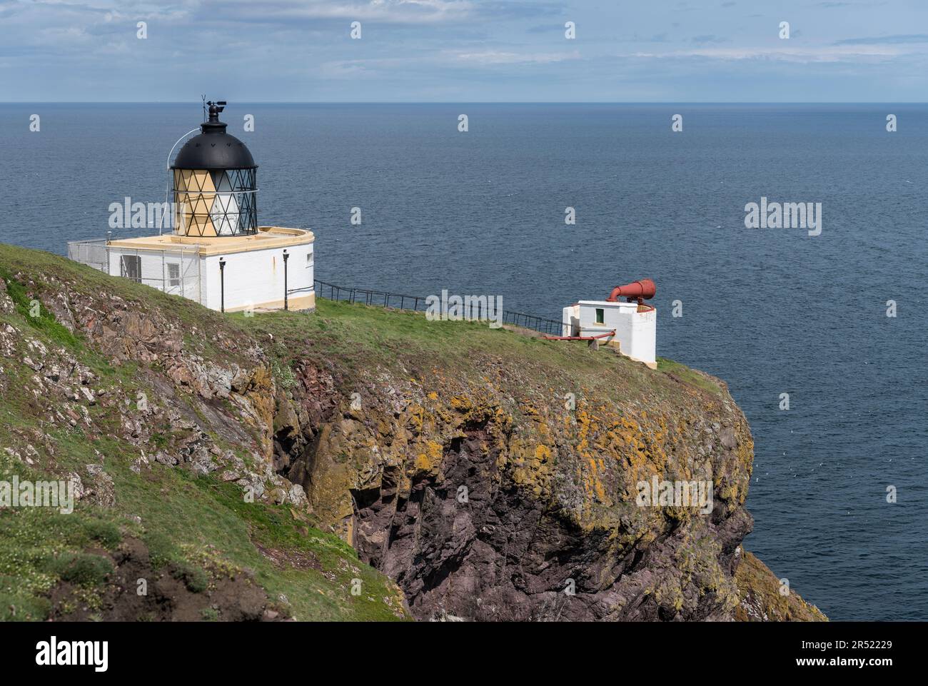 Faro di St Abbs Head e foghorn in cima a scogliere rocciose con mare blu calmo e piano e orizzonte sullo sfondo. Foto Stock