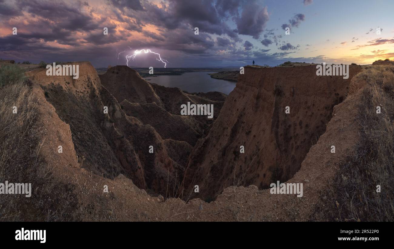 Vista di un turista irriconoscibile in piedi su una scogliera in una valle oscura di una grande gola, mentre ammira la vista pittoresca Foto Stock