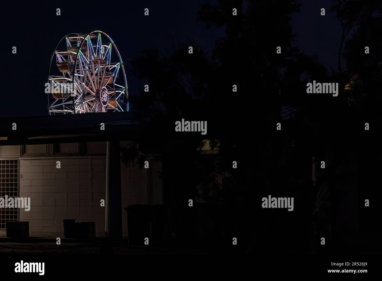 Vista in lontananza di una ruota panoramica illuminata di luce contro il cielo notturno. Foto Stock