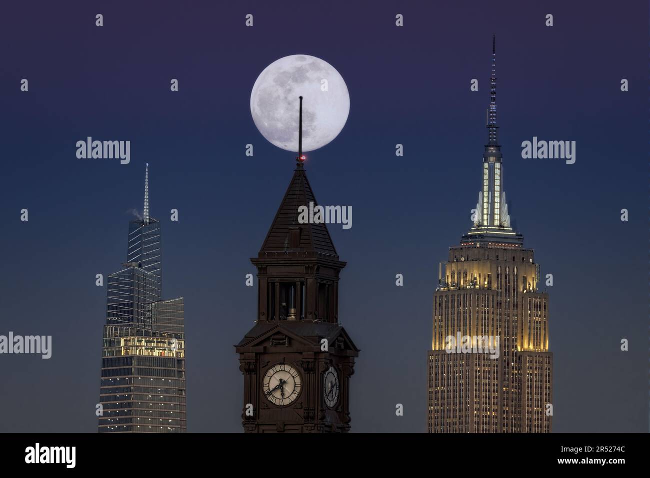 La luna piena sorge dietro la Torre dell'Orologio di Lackawanna a Hoboken, New Jersey, accanto all'iconico Empire state Building e al 1 Vanderbilt Foto Stock