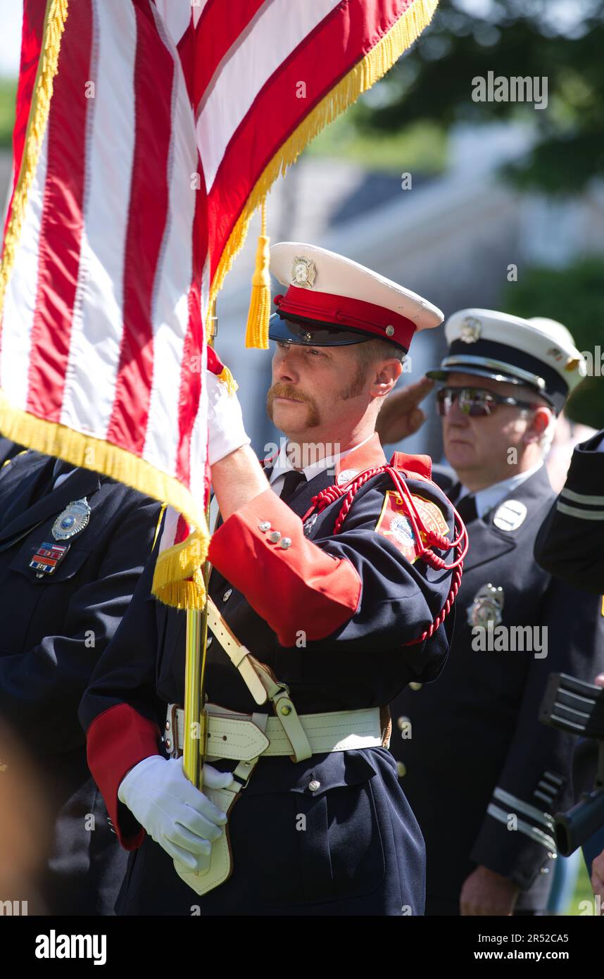 Evento del Memorial Day. Dennis, Massachusetts, (Cape Cod) , Stati Uniti. Un vigile del fuoco guardia d'onore con la bandiera americana Foto Stock