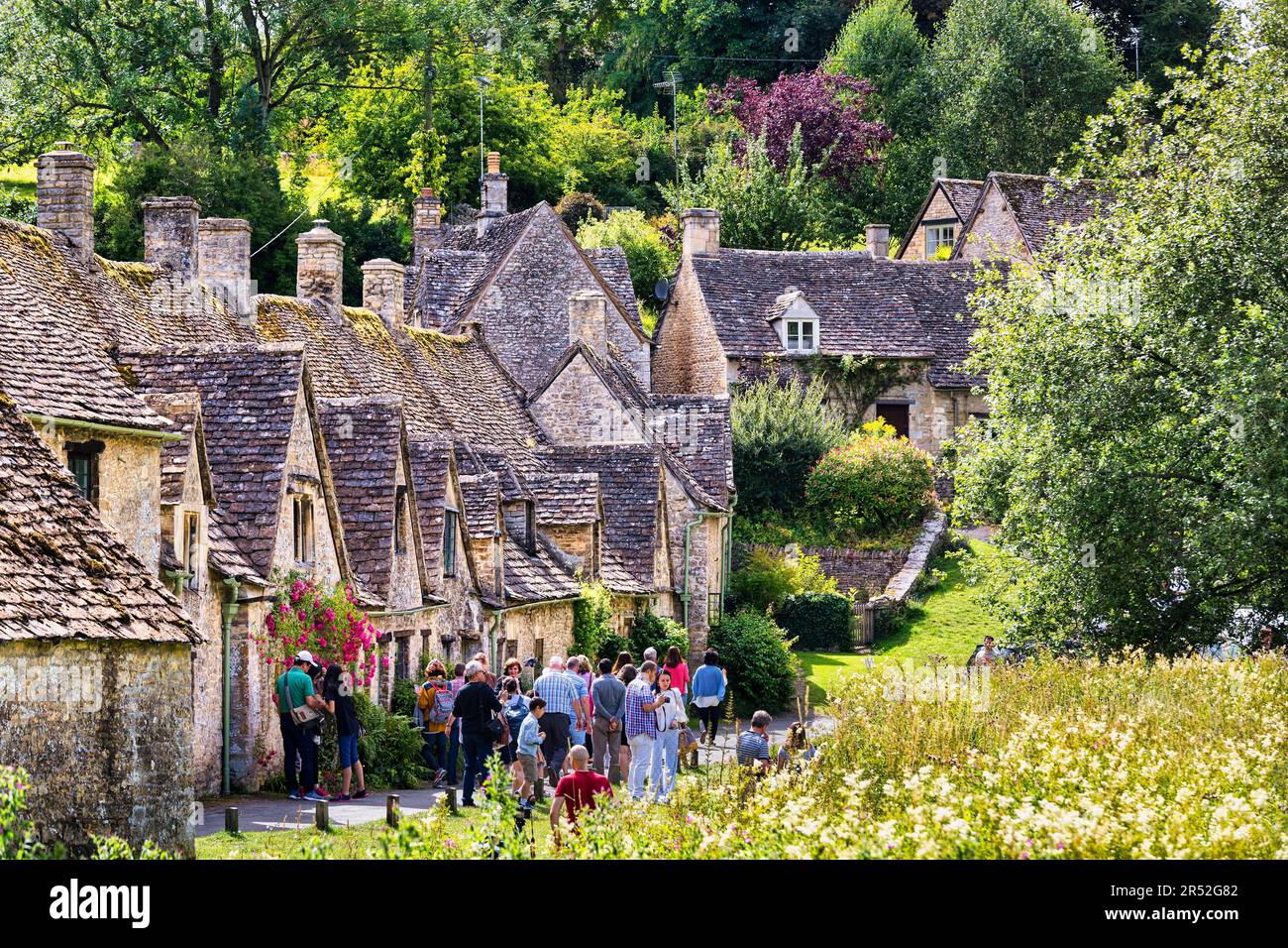 Gruppo di turisti nella famosa Arlington Row, pittoresche case elencate, Bibury, Cotswolds, Gloucestershire, Inghilterra, Regno Unito Foto Stock