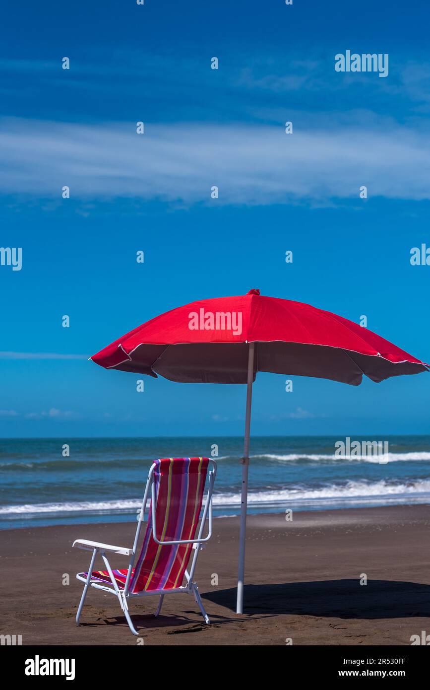 Sdraio a strisce colorate con ombrello rosso sulla riva del mare Foto stock  - Alamy