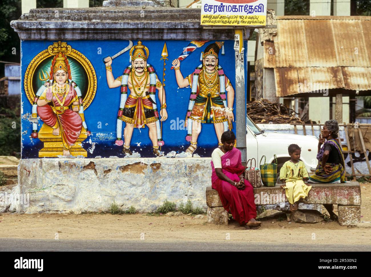Abitanti del villaggio in attesa di un autobus, seduti su una panchina di pietra a Pathamadai Pattamadai vicino Tirunelveli Thirunelveli, Tamil Nadu, India del Sud, India, Asia Foto Stock