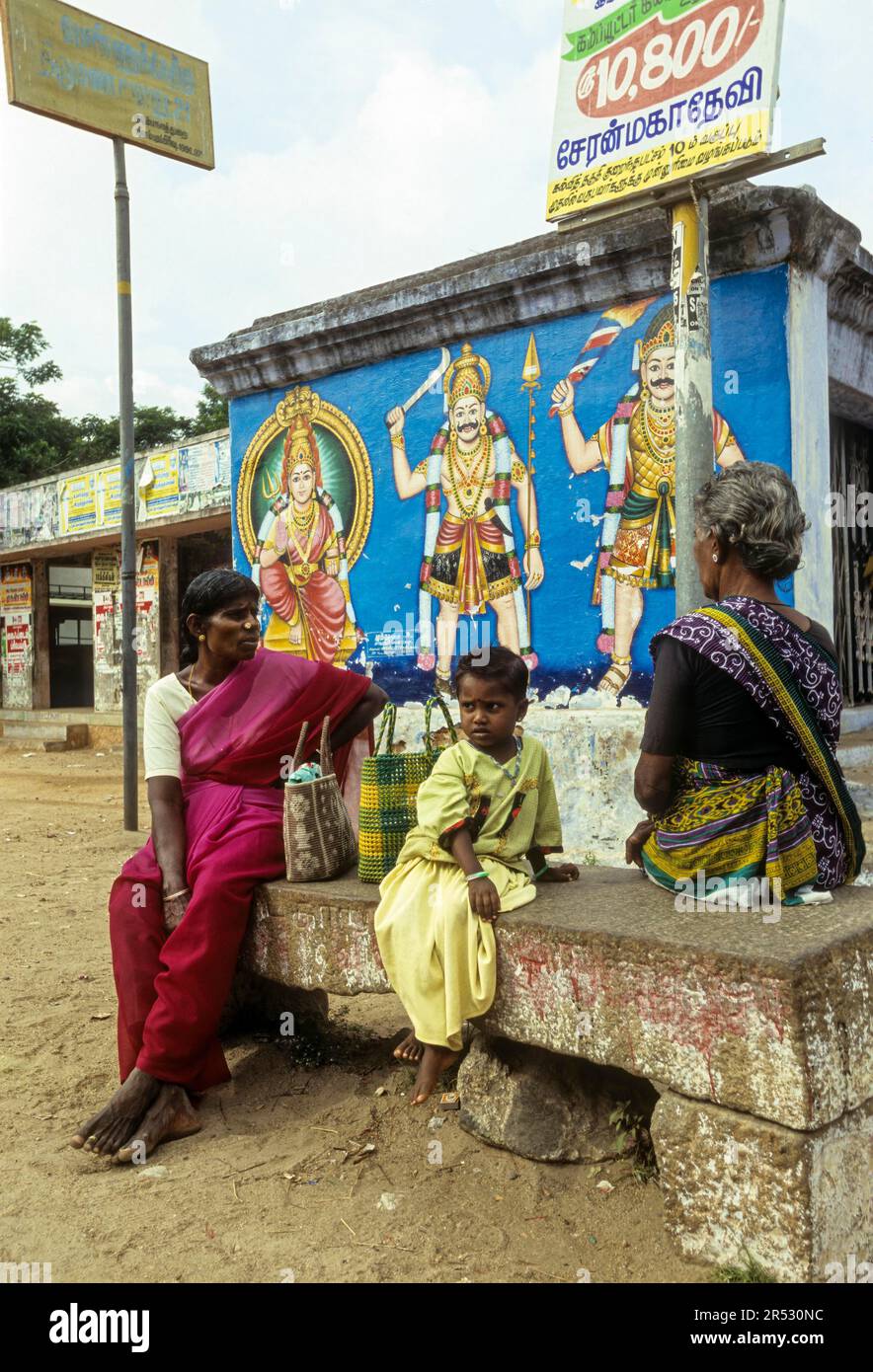 Abitanti del villaggio in attesa di un autobus, seduti su una panchina di pietra a Pathamadai Pattamadai vicino Tirunelveli Thirunelveli, Tamil Nadu, India del Sud, India, Asia Foto Stock