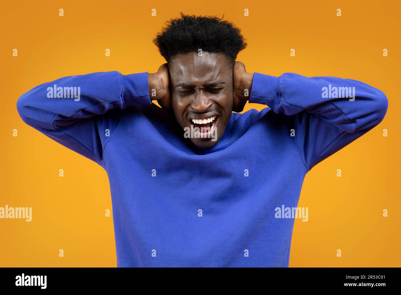 Il giovane africano urla, coprendo le orecchie di giallo Foto Stock