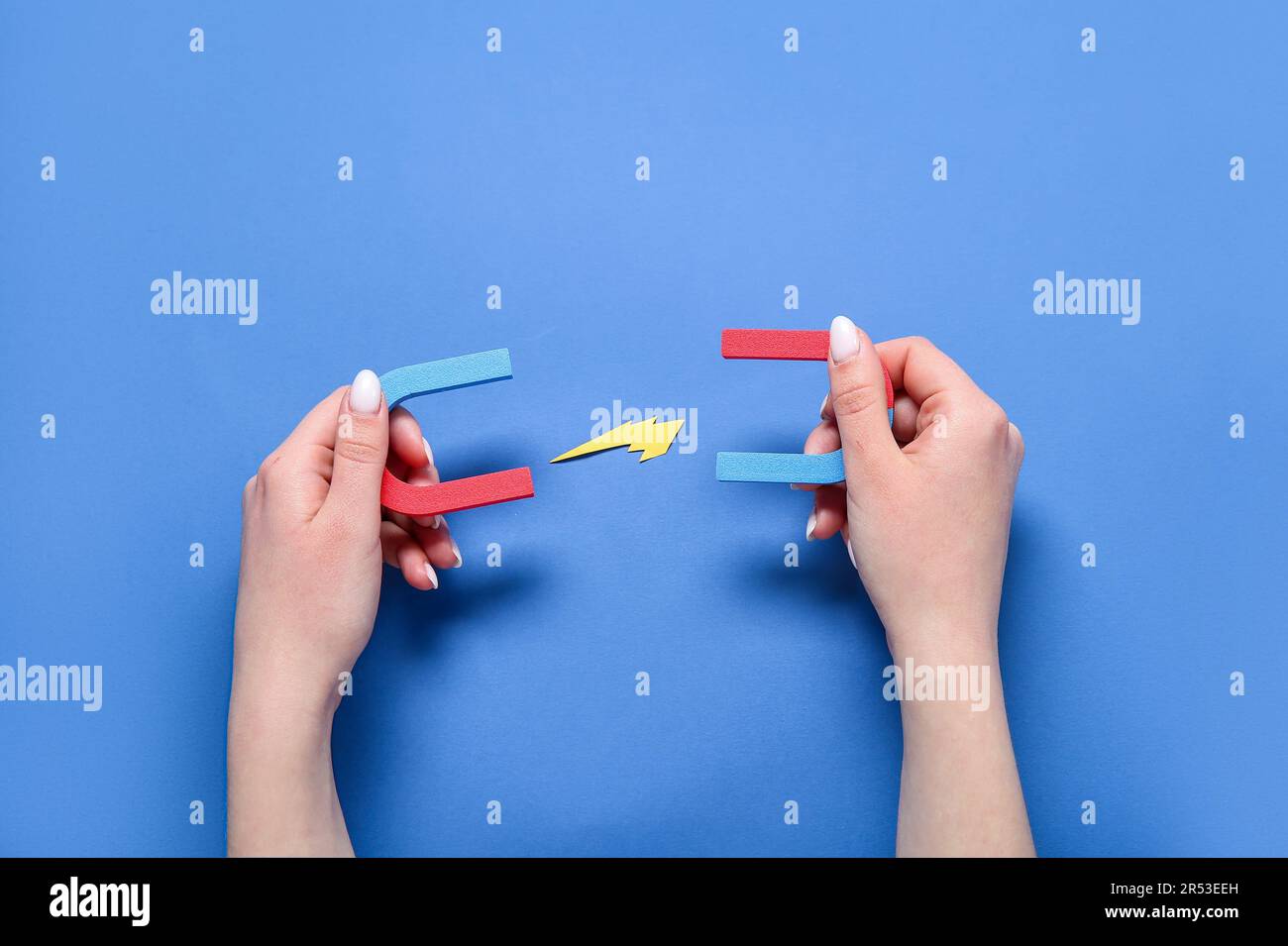 Mano femmina con mini magneti e lampo di carta su sfondo blu Foto Stock