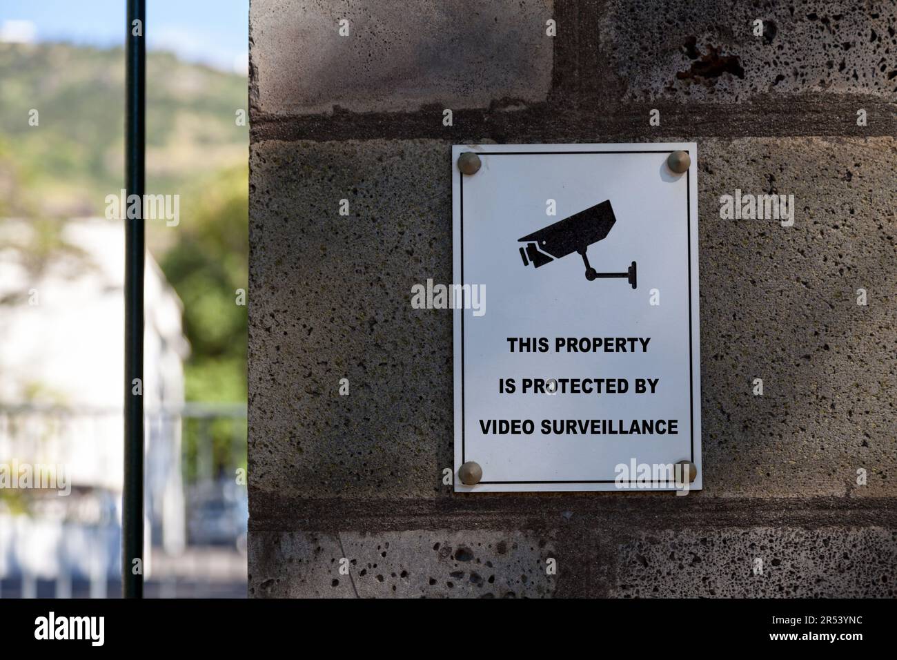Un cartello bianco su una colonna di pietra che dice "questa proprietà è protetta dalla videosorveglianza". Foto Stock