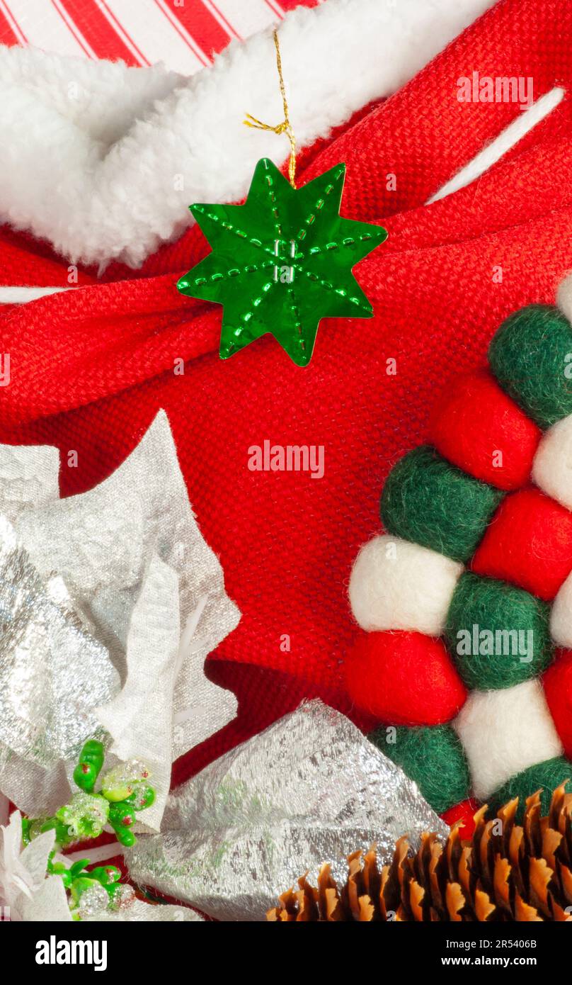 Esposizione di Natale primo piano di ornamento verde, tessuto rosso e bianco con poinsettia e piccolo spazio di testo centrale con texture. Foto Stock