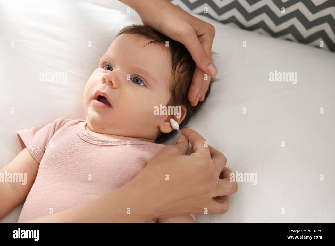Madre pulizia orecchie del suo bambino con cotton fioc sul letto