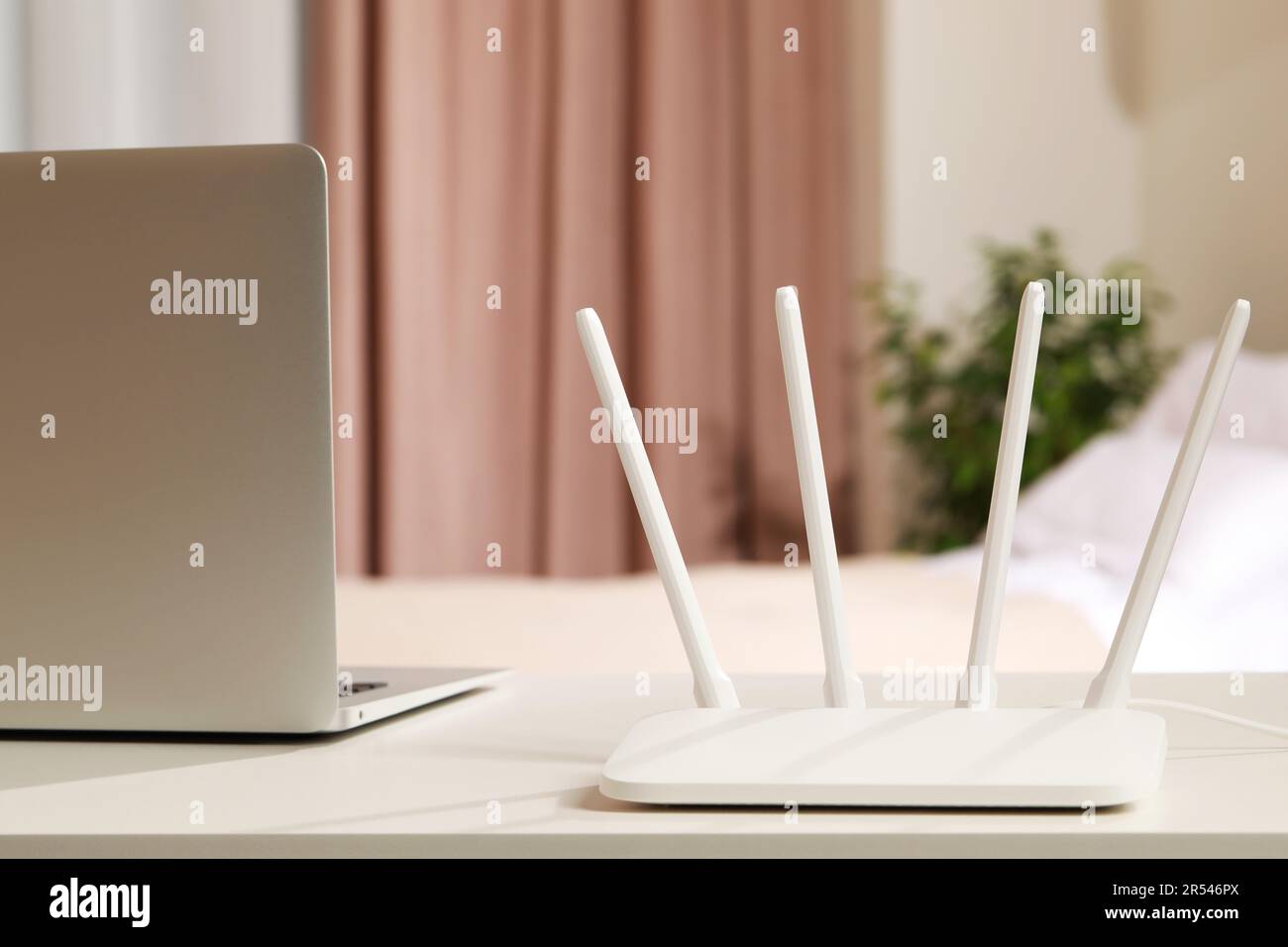 Nuovo router Wi-Fi vicino al computer portatile su un tavolo bianco in ambienti chiusi Foto Stock
