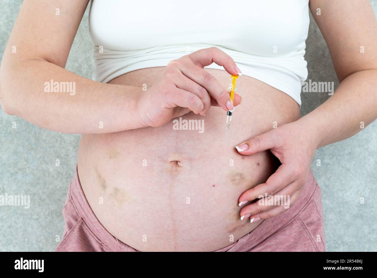 Donna incinta che fa l'iniezione nello stomaco Foto Stock