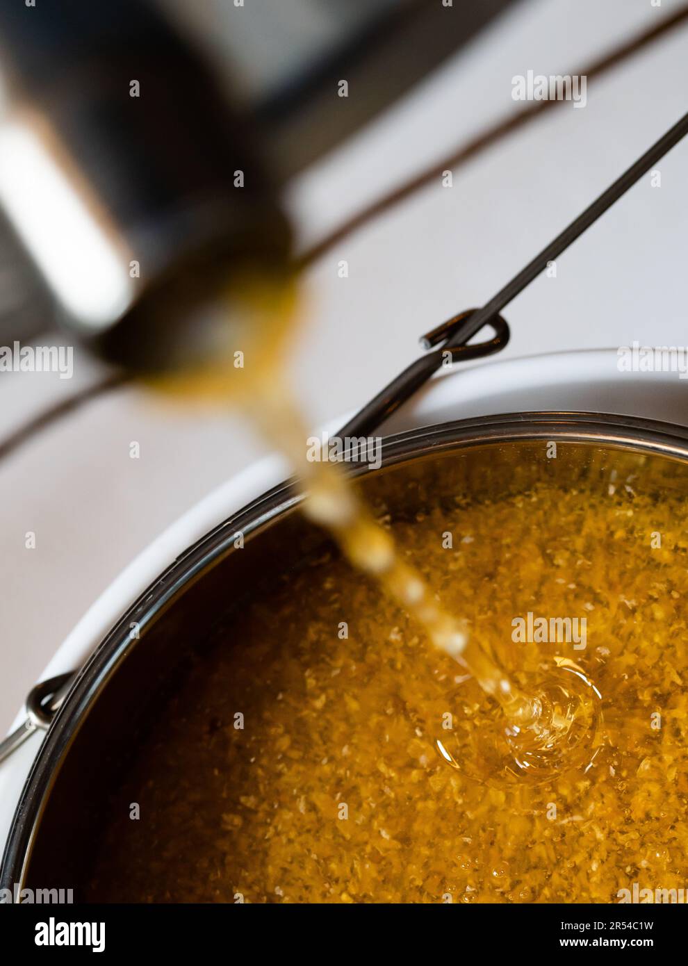 Il miele che fuoriesce da un estrattore e si trasforma in un filtro a rete durante l'estrazione Foto Stock