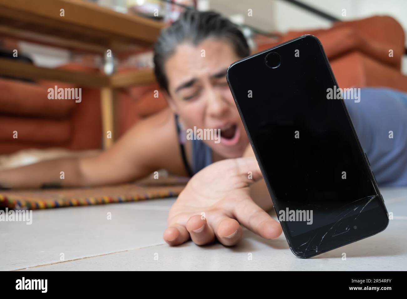 Il telefono cellulare si blocca a terra. In background, una persona fuori fuoco gestisce, cercando di afferrarla. Foto Stock