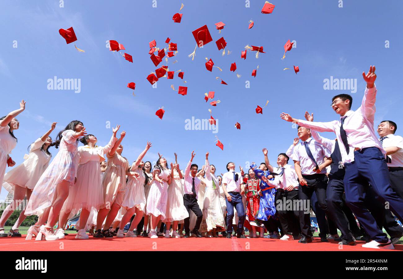ZHANGYE, CINA - 31 MAGGIO 2023 - studenti di diciotto anni lanciano in aria i loro "cappelli adulti" durante la cerimonia di maturità nella città di Zhangye, GA Foto Stock