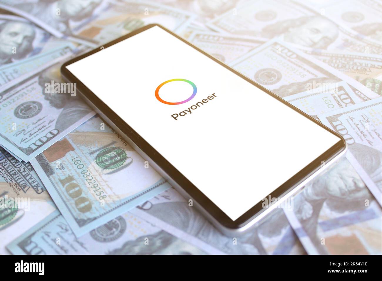 Logo Payoneer visualizzato sullo smartphone in cima a un mucchio di soldi. Concetto di profitto aziendale Foto Stock